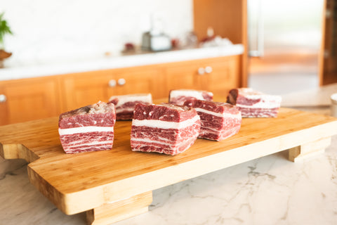 Raw beef blocks on a wooden cutting board in a kitchen setting