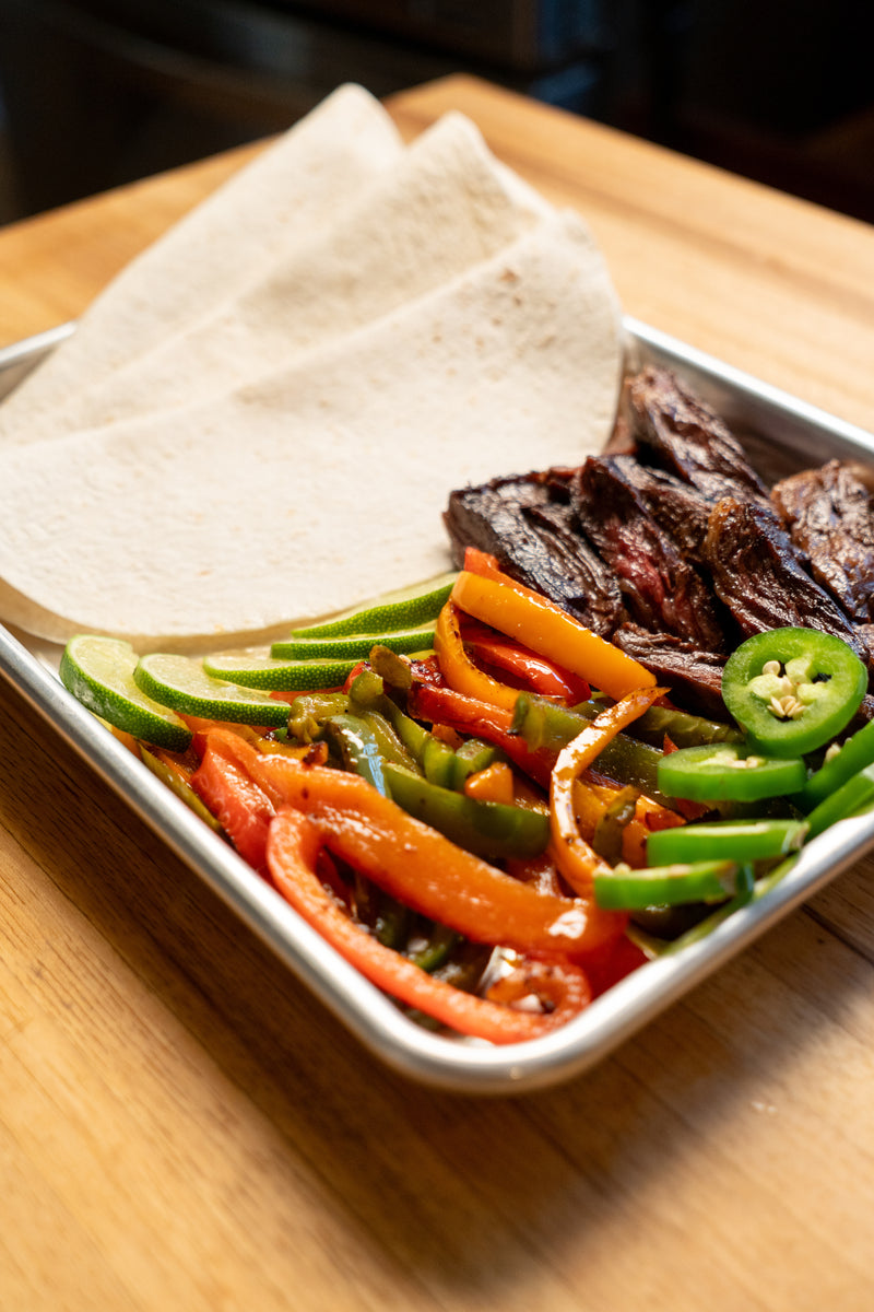Platter of sliced vegetables and wagyu meat on a wooden surface