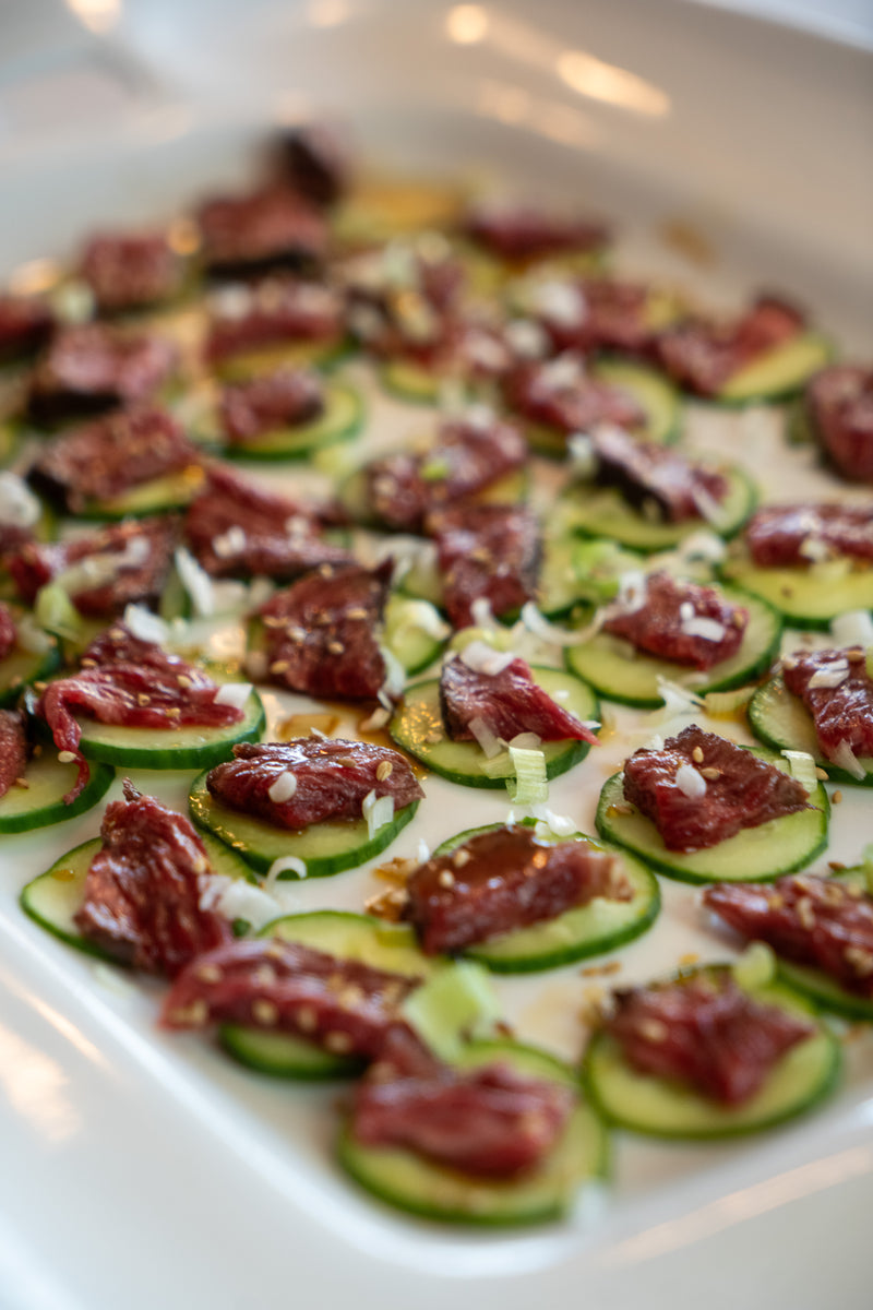 Cucumber slices with wagyu steak on a white plate